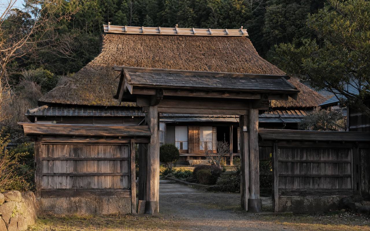 南房総の茅葺き古民家。江戸末期築の入母屋造りで、長屋門と広い庭を持つ歴史的木造邸宅の外観写真。
